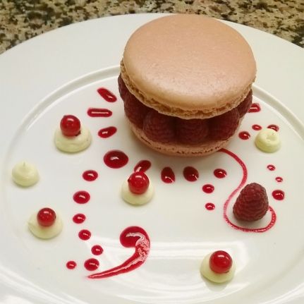 Plating a rapsberry and anis macaron with raspberry coulis and anis cream